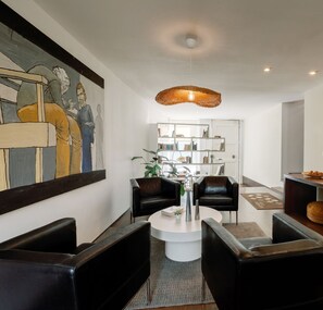 A modern living room with a round coffee table, black leather sofas, a bookshelf, and a large painting on the wall. - Olala Fine Arts Studios (Porto)