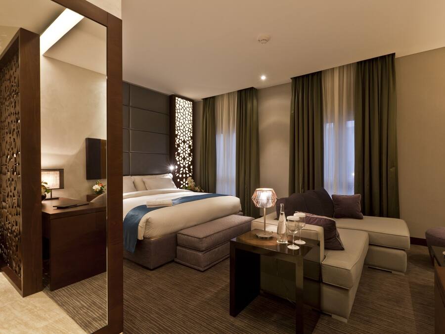 Una habitación de hotel moderna con cama, sofá, escritorio y mesita de noche.
