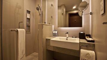 Une salle de bain moderne dotée d’une douche à parois de verre, d’un lavabo avec un miroir et de serviettes portant la marque « ZUBARAH ».