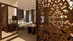 Ein modernes Hotelzimmer mit einem großen Bett, einem Schreibtisch und einem dekorativen Raumteiler.