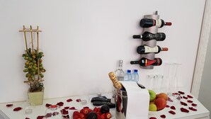 Una mesa con un botellero, una botella de champán, un frutero y pétalos de rosa dispersos.