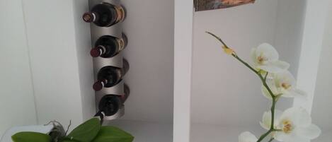 Una mensola bianca con quattro bottiglie di vino e un libro.