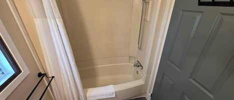 A bathroom with a bathtub, a shower, and a towel rack.