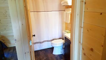 A bathroom with a wooden floor, a white toilet, and a shower curtain.