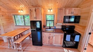A compact kitchen with wooden cabinetry, a refrigerator, a stove, a microwave, and a sink. - Abbot Trailside Lodging (Abbot)