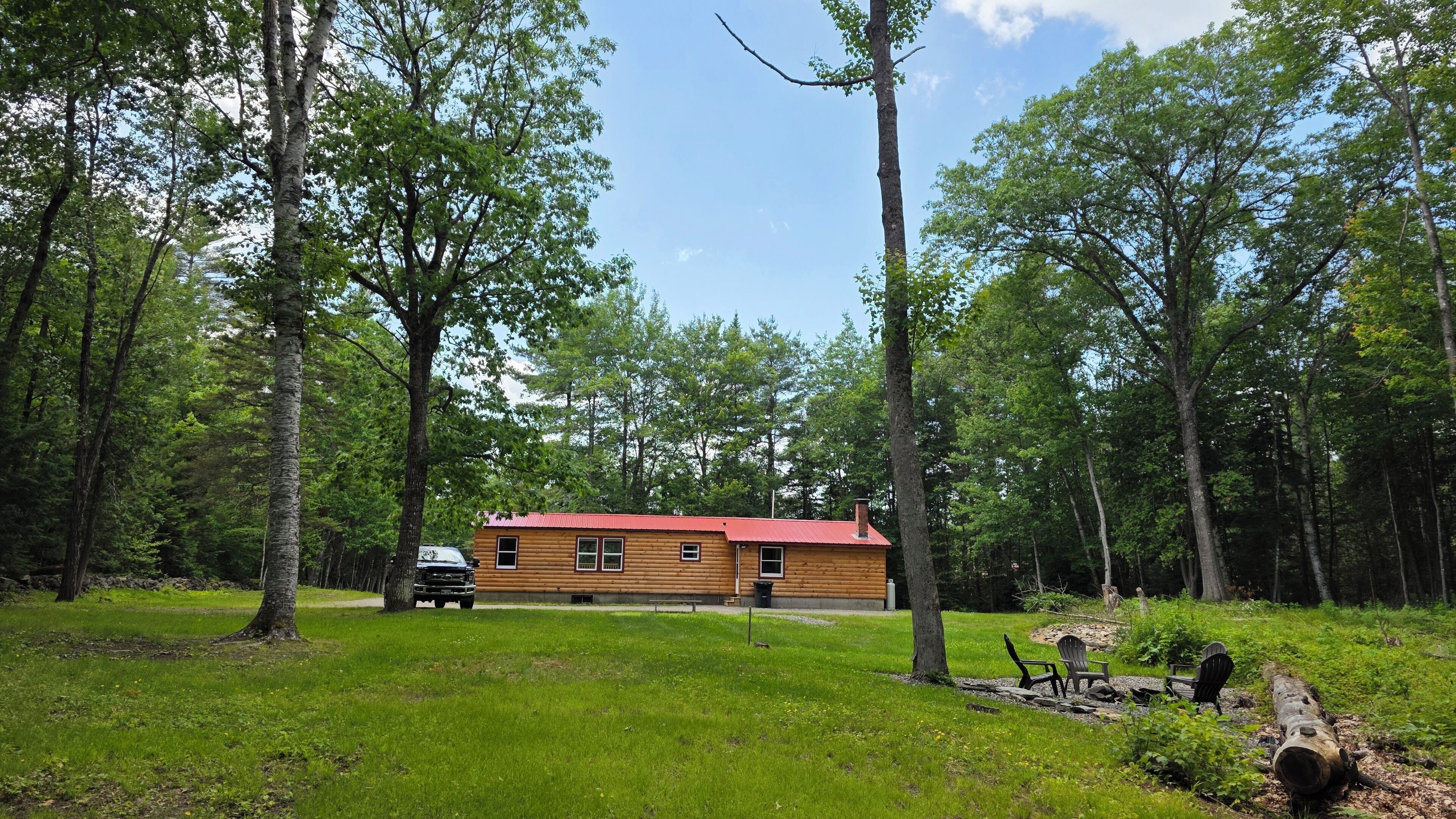 Une cabane avec un toit rouge, entourée d’une forêt.