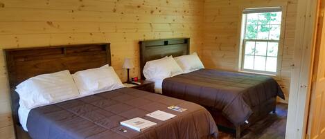 Une chambre dans un chalet en bois, avec deux lits, une table de chevet et une fenêtre.