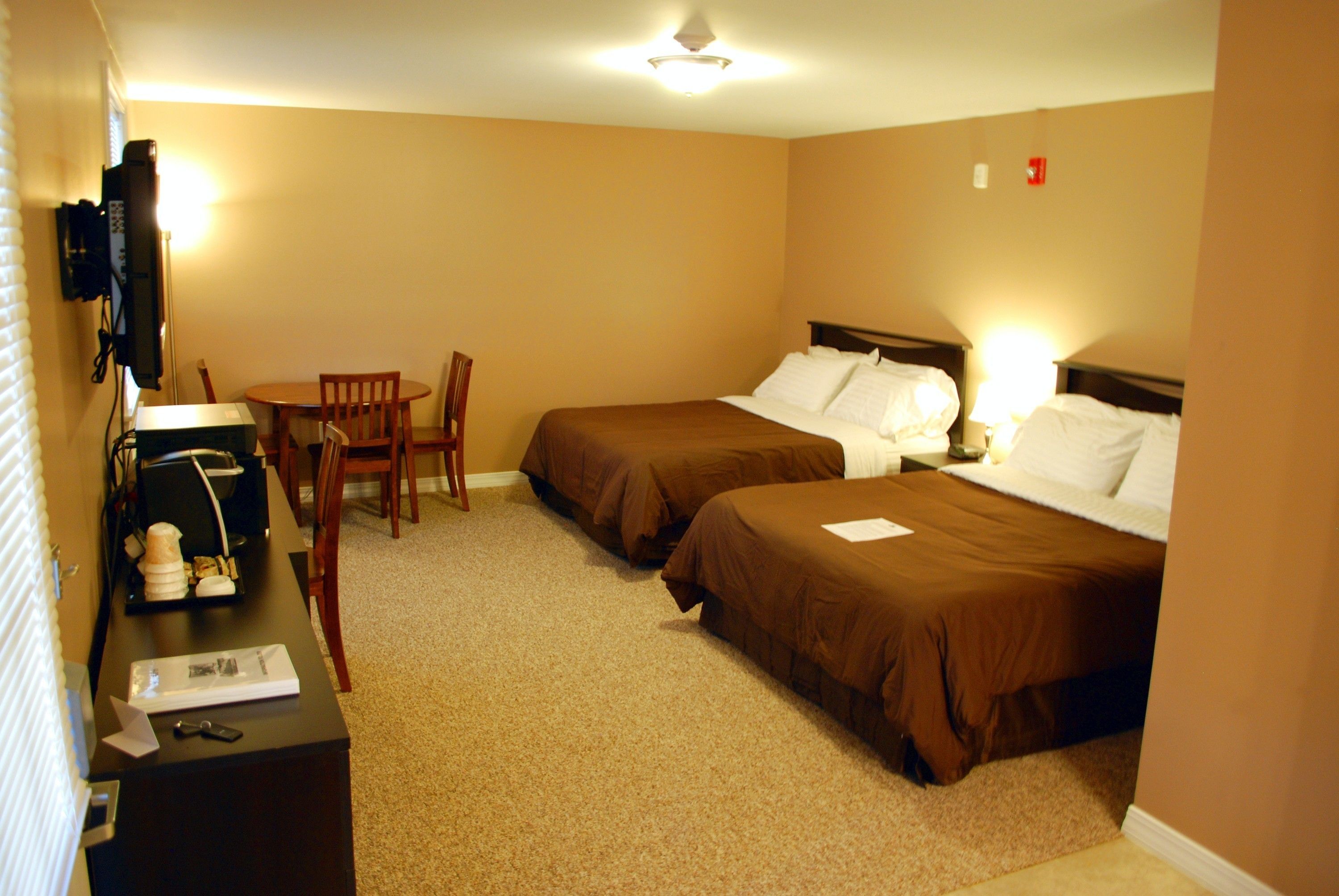 A hotel room with two beds, a desk with a computer, a chair, and a small table.