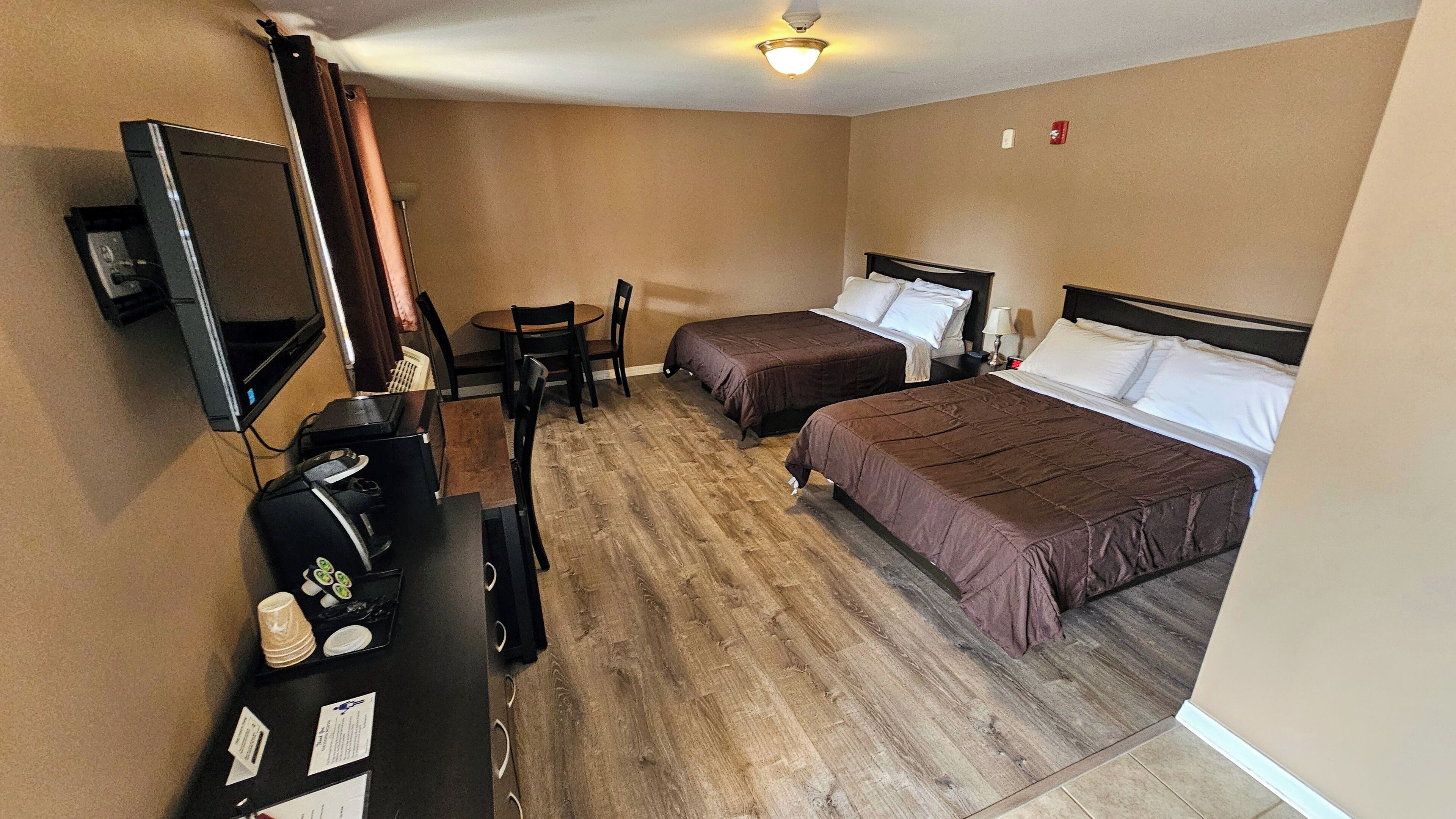 A hotel room with two beds, a desk with a computer, a chair, and a television.
