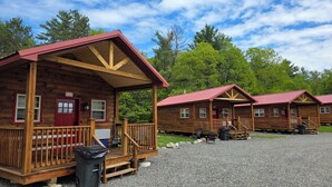 A row of log cabins with wooden decks and red roofs, surrounded by trees. - Abbot Trailside Lodging (Abbot)