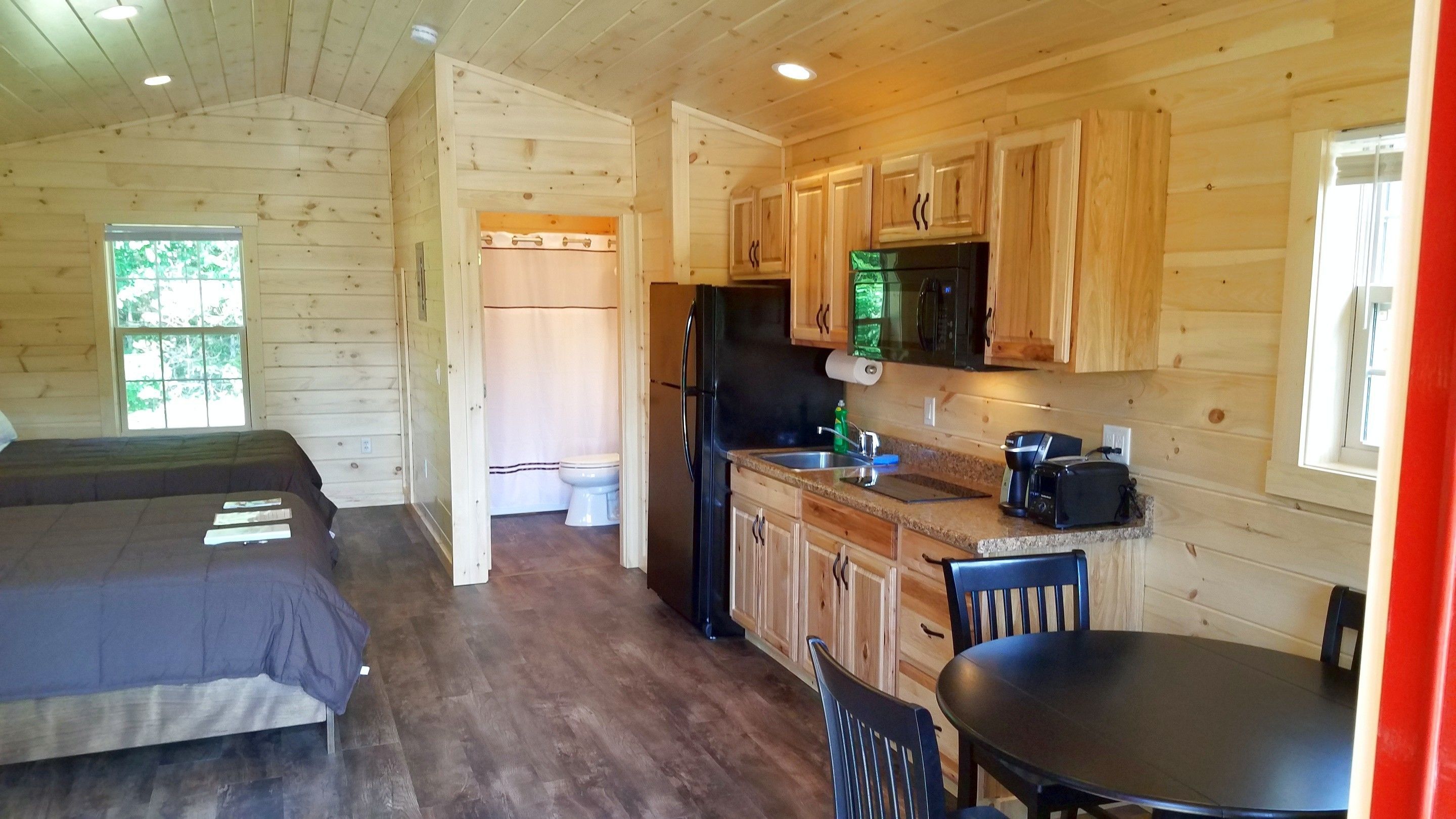 A cabin with two bedrooms, a kitchen with wooden cabinets, a dining area, and a bathroom.