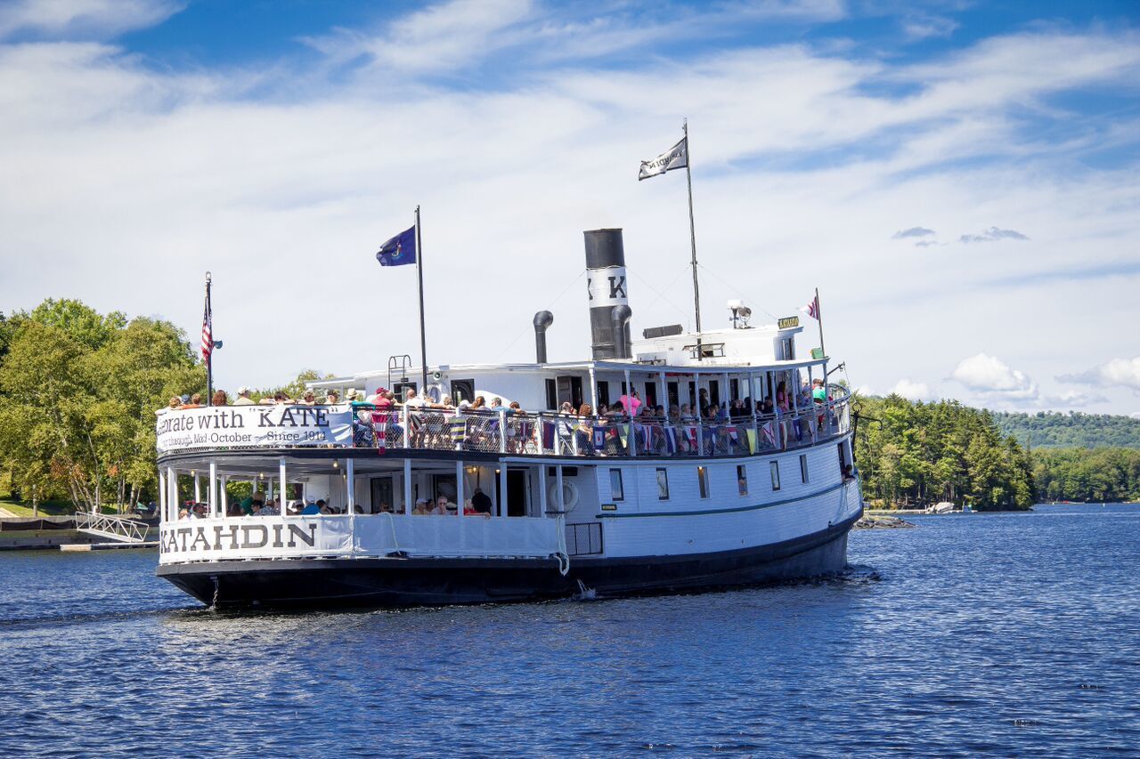 A riverboat with a deck area for passengers, a cabin structure, and flags.