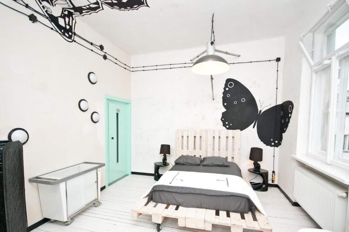 A bedroom with a wooden bed, a green door, a ceiling fan, and a window.