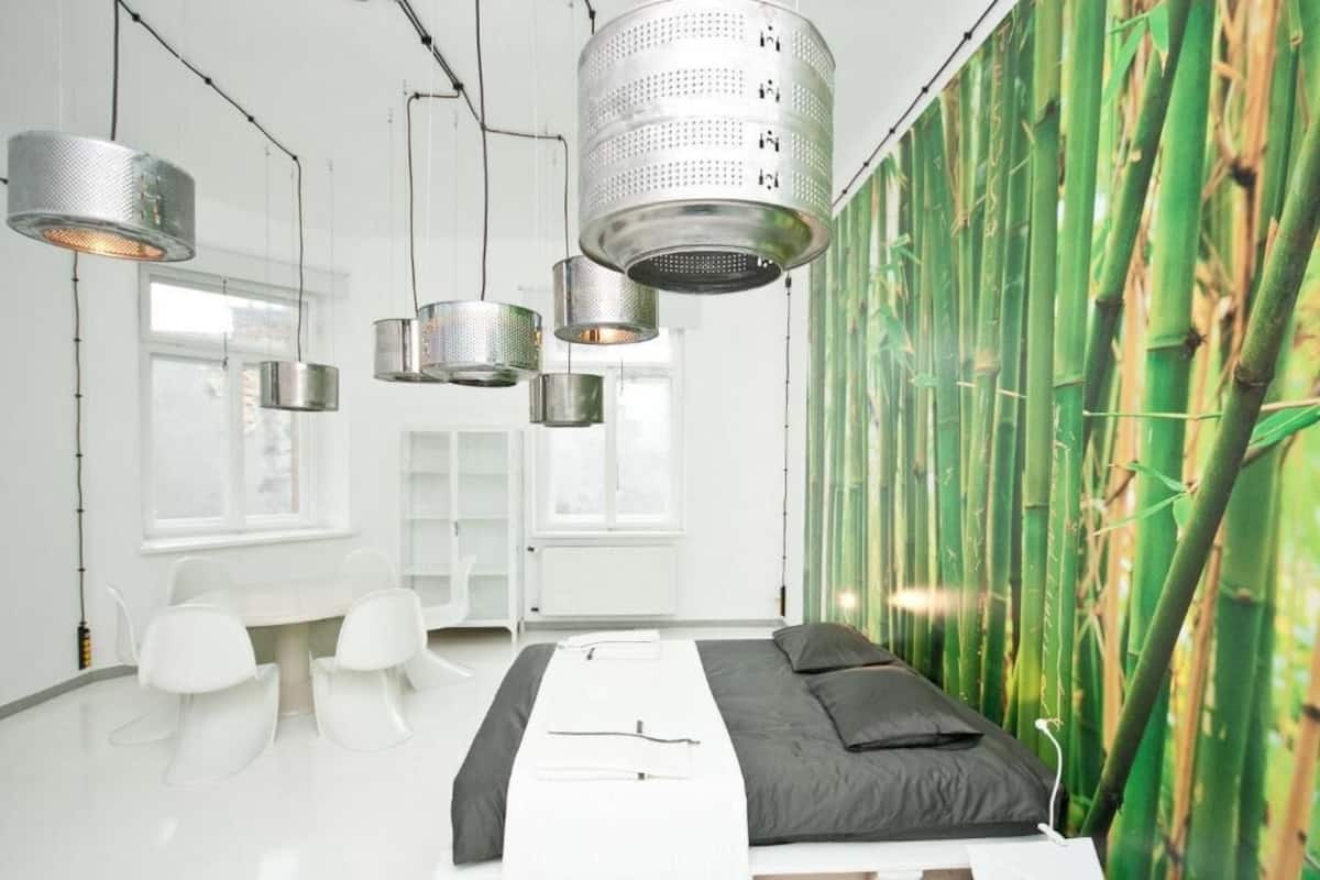 A modern bedroom with a bed, white chairs, and a bamboo wall.