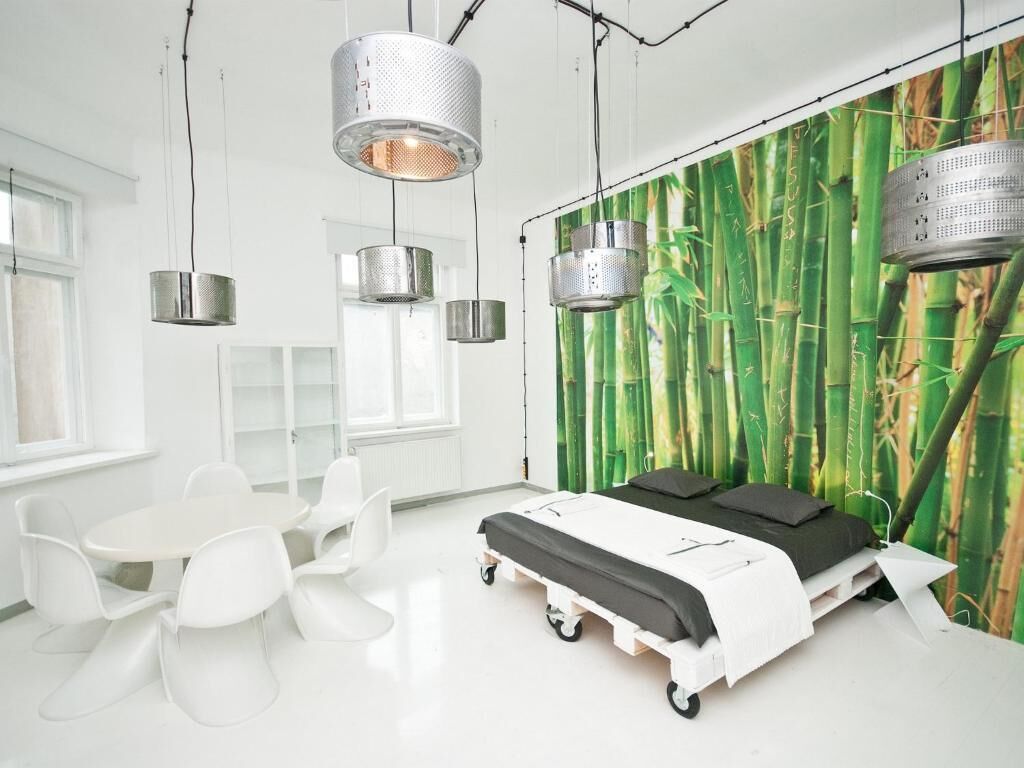 A modern room with a bed, white chairs, a table, and a bamboo wallpaper.