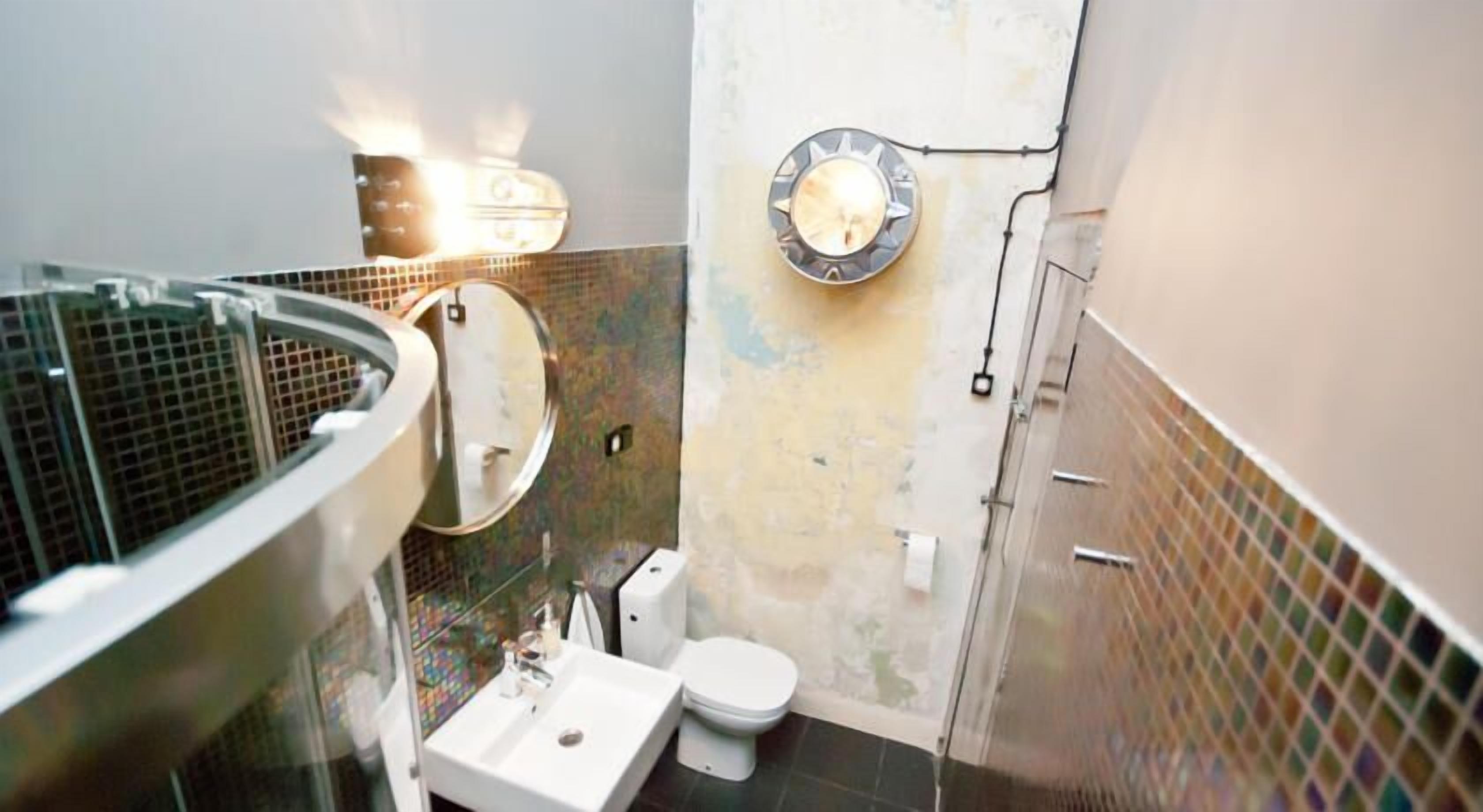 A bathroom with a toilet, sink, and a large mirror.
