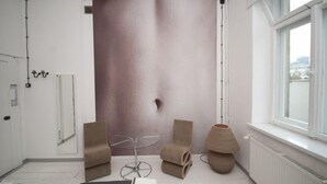 A modern room with a large window, a mirror, a round table, and two chairs. - Lofthotel Sen Pszczoły (Warsaw)
