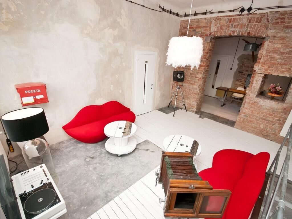 Ein modernes Wohnzimmer mit einem roten Sofa, einem weißen Couchtisch und einer DJ-Anlage.