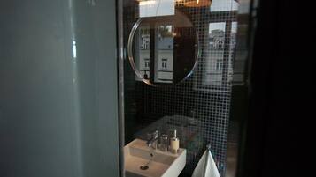 A bathroom with a glass partition, a sink, a mirror, and a towel rack.