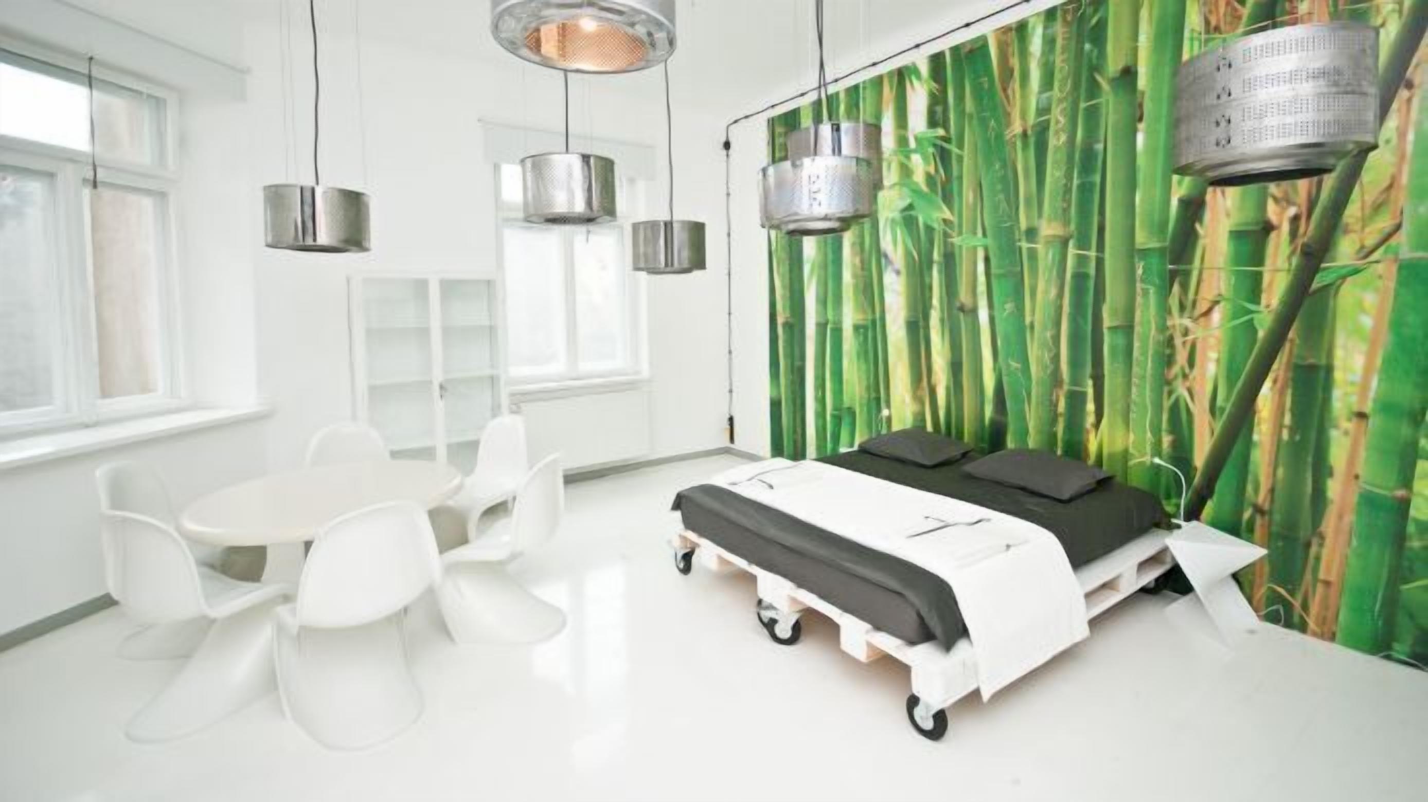 Una habitación moderna con una cama, sillas blancas y una pared de bambú.