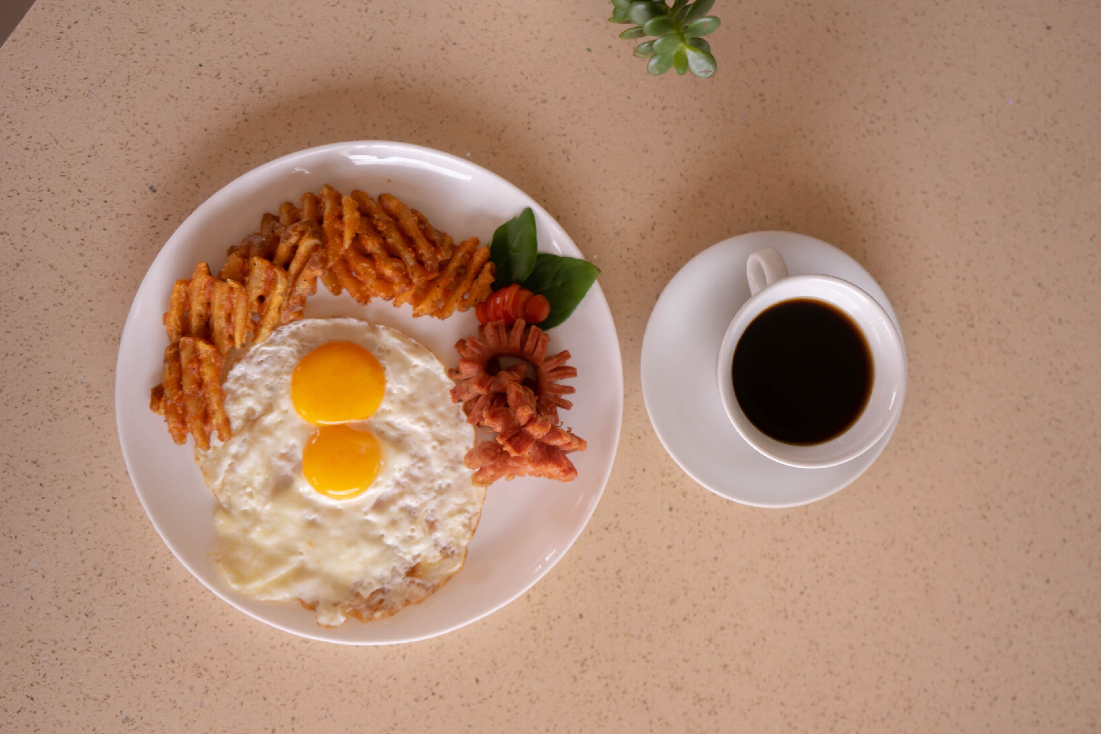 Un plato con huevos, patatas ralladas y tocino, además de una taza de café sobre una mesa.