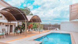 An outdoor swimming pool with lounge chairs and a covered seating area.