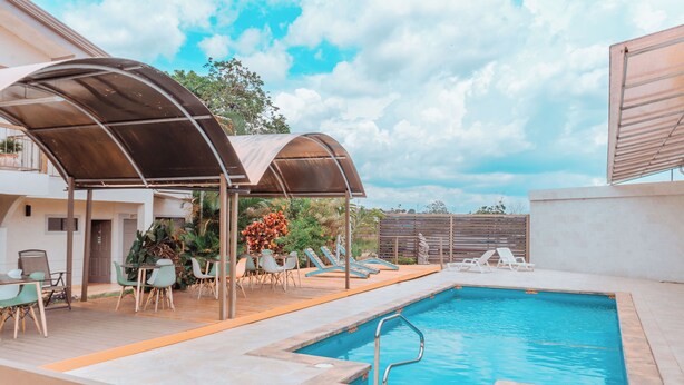 An outdoor swimming pool with lounge chairs and a covered seating area. - Hotel Zima (San Isidro de El General)
