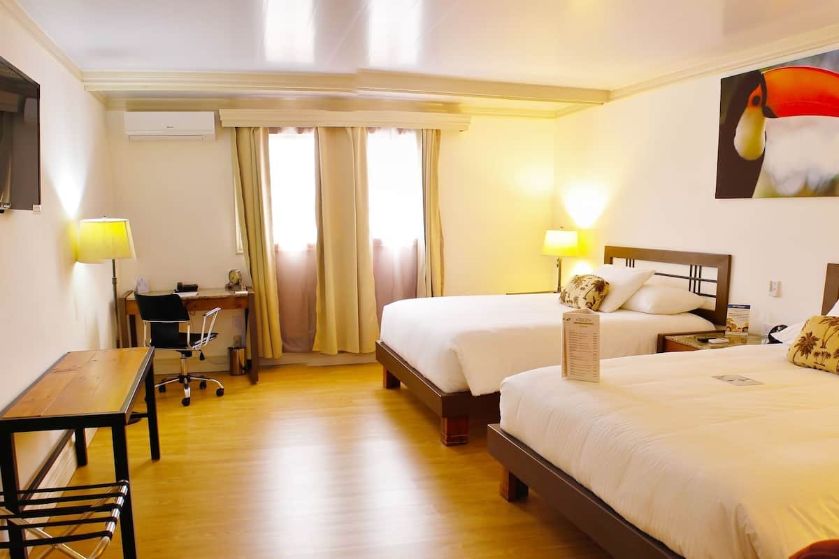 A hotel room with two beds, a desk, a chair, a TV, and a painting on the wall.