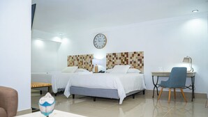 A hotel room with two beds, a desk, a chair, a lamp, and a wall clock. - Hotel Zima (San Isidro de El General)
