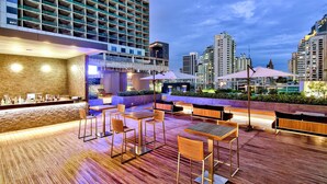 A rooftop bar with wooden flooring, seating, and a bar area with bottles. - Radisson Blu Plaza Bangkok (Bangkok)