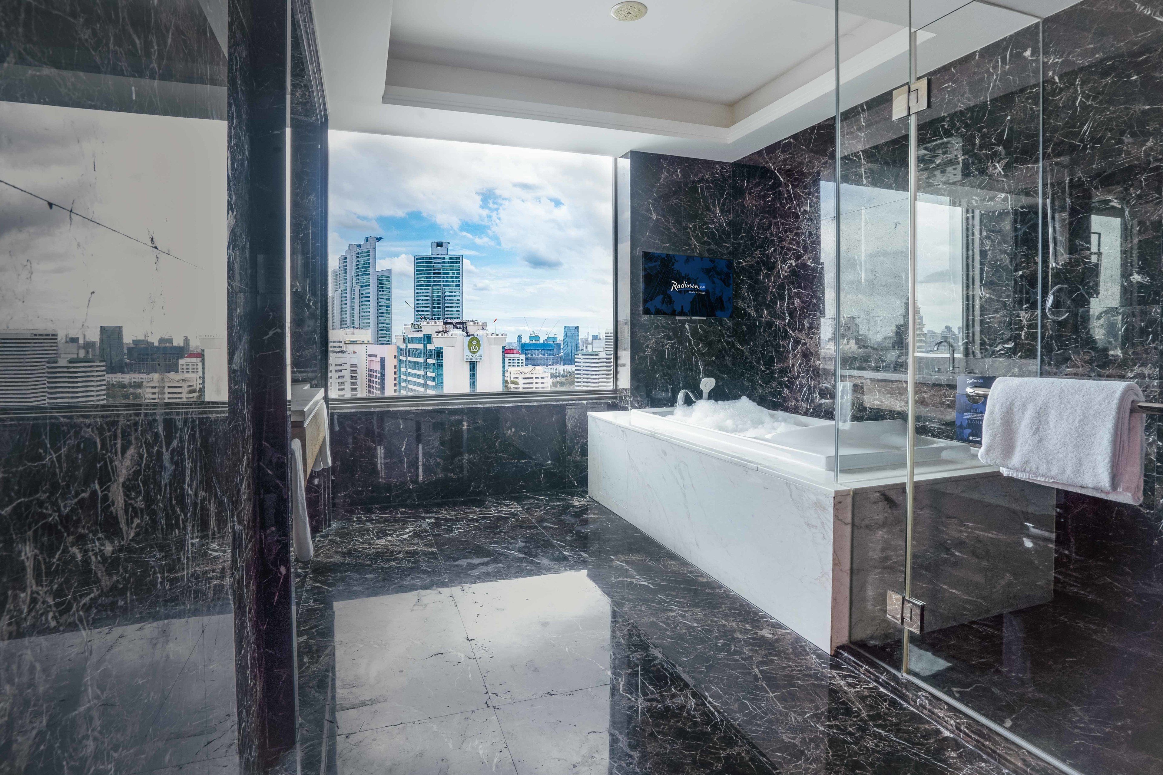 A modern bathroom with a large mirror, a bathtub, and a glass-enclosed shower area.