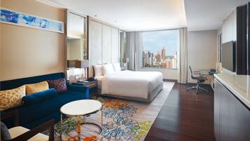 Una habitación de hotel con una cama, un sofá, un escritorio y vistas a la ciudad.