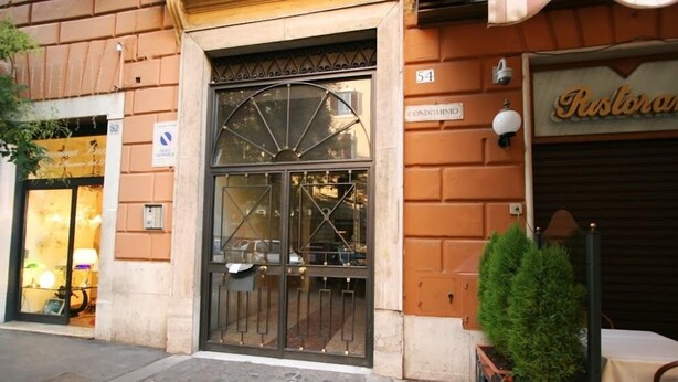 Un edificio con un gran portón metálico, un letrero de restaurante y el número '54' que indica un condominio.