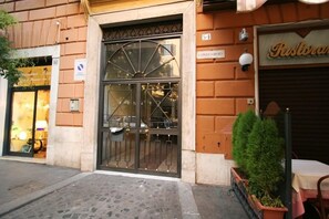 A building with a large metal gate, a restaurant sign, and a number '54' indicating a condominium. - San Peter Angels (Rome)