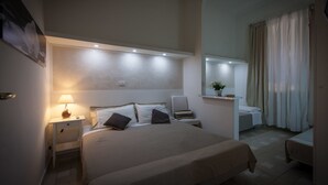 Una habitación de hotel con una cama grande, mesitas de noche, un escritorio y una silla.
