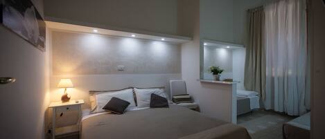 A hotel room with a large bed, bedside tables, a desk, and a chair.