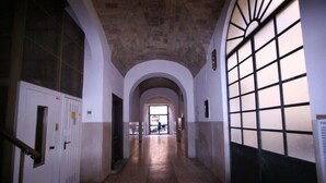 Un pasillo con techos abovedados, un ventanal con diseño de cuadrícula y una puerta con manija.