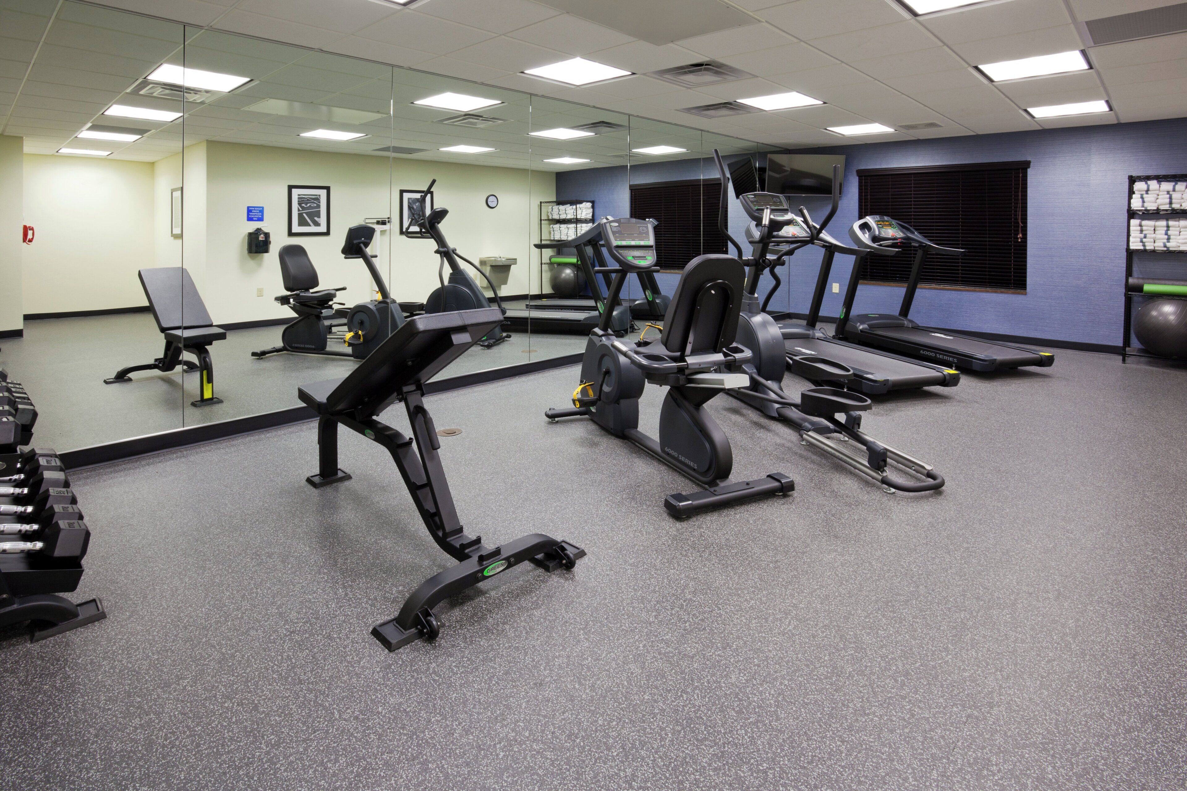 A gym with various exercise equipment including treadmills, an elliptical, and free weights.