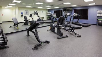 A gym with various exercise equipment including treadmills, an elliptical, and free weights.