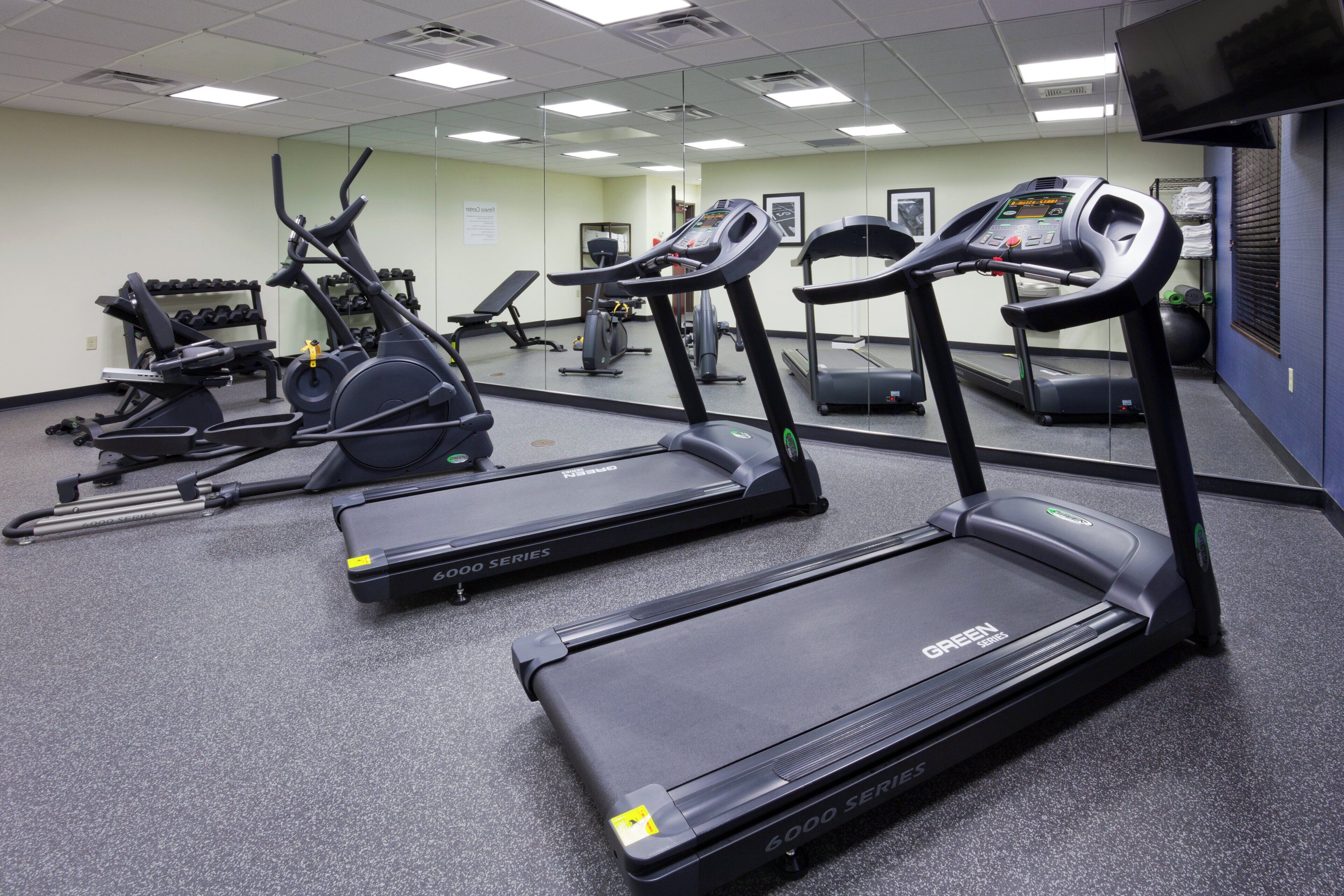 Un gimnasio con cintas de correr, bicicletas estáticas y máquinas de pesas.