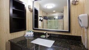 A bathroom with a large mirror, a sink, and a hairdryer.