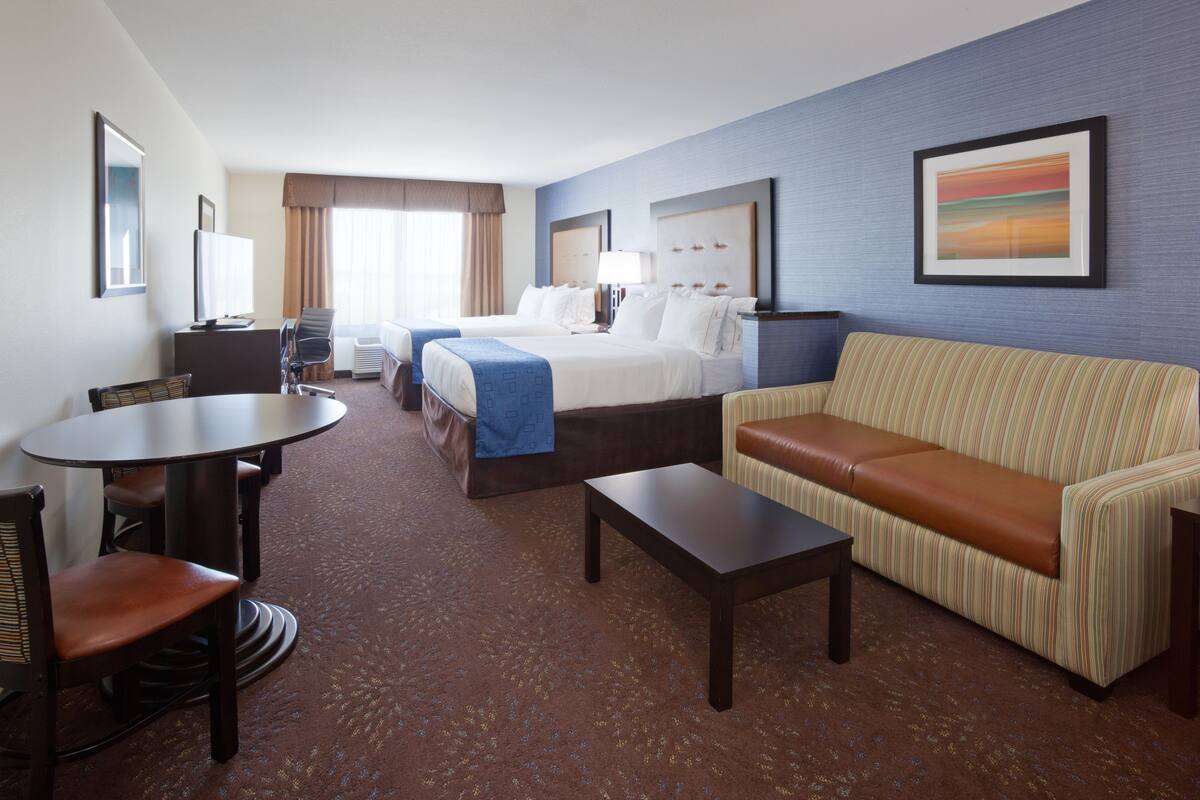 A hotel room with a bed, a sofa, a desk, and a chair.