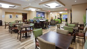 A hotel lobby with multiple seating areas, including a central bar and several tables and chairs.
