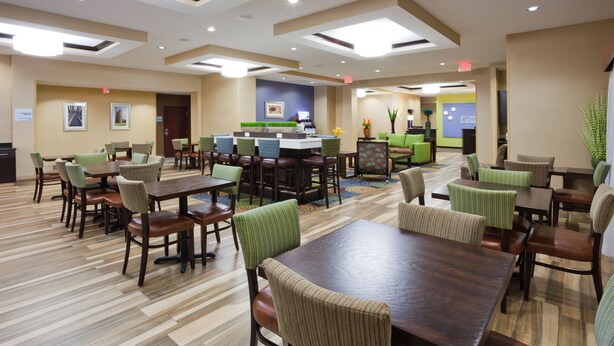 Un hall d’hôtel doté de plusieurs espaces aménagés avec des sièges, notamment un bar central ainsi que plusieurs tables et chaises.