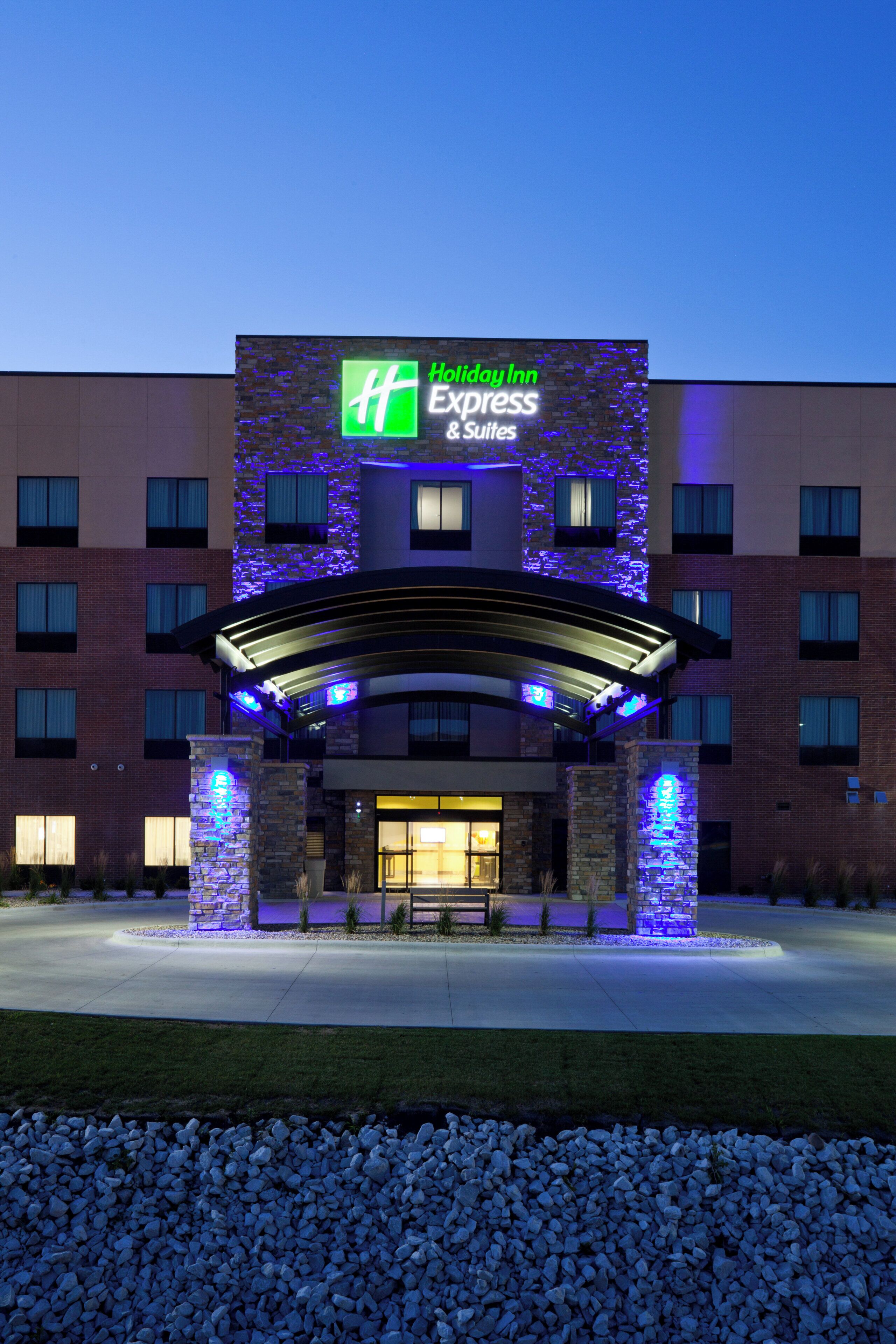 A Holiday Inn Express & Suites hotel with a modern brick facade and illuminated signage.