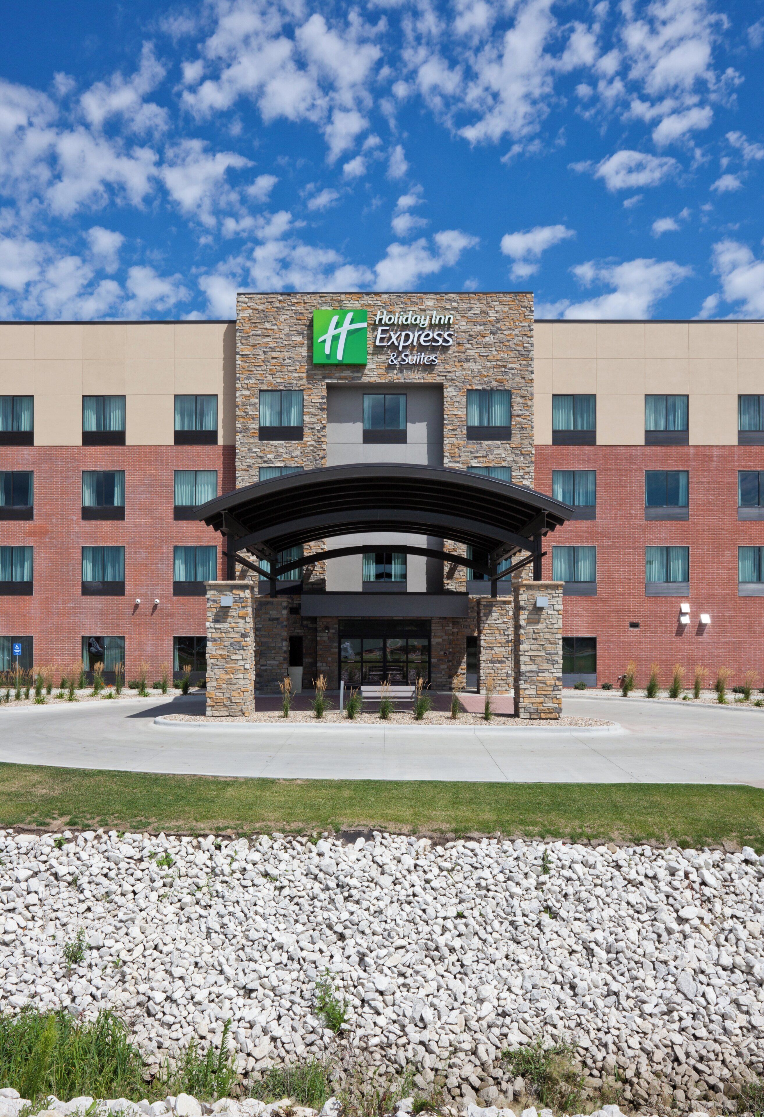 A Holiday Inn Express & Suites building with a stone facade, multiple windows, and a covered entrance.