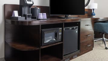 A compact kitchenette with a microwave, coffee maker, and a flat-screen TV on a wooden cabinet.