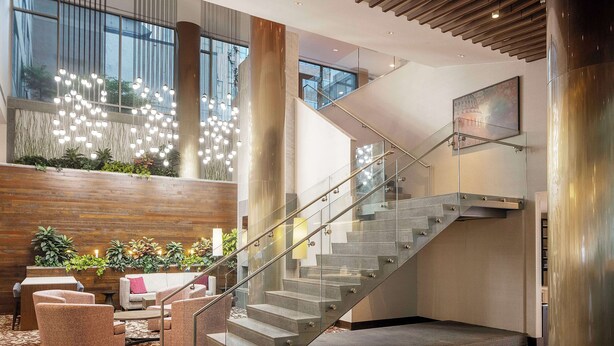 Eine moderne Lobby mit Glastreppe, Sitzgelegenheiten und dekorativer Beleuchtung.