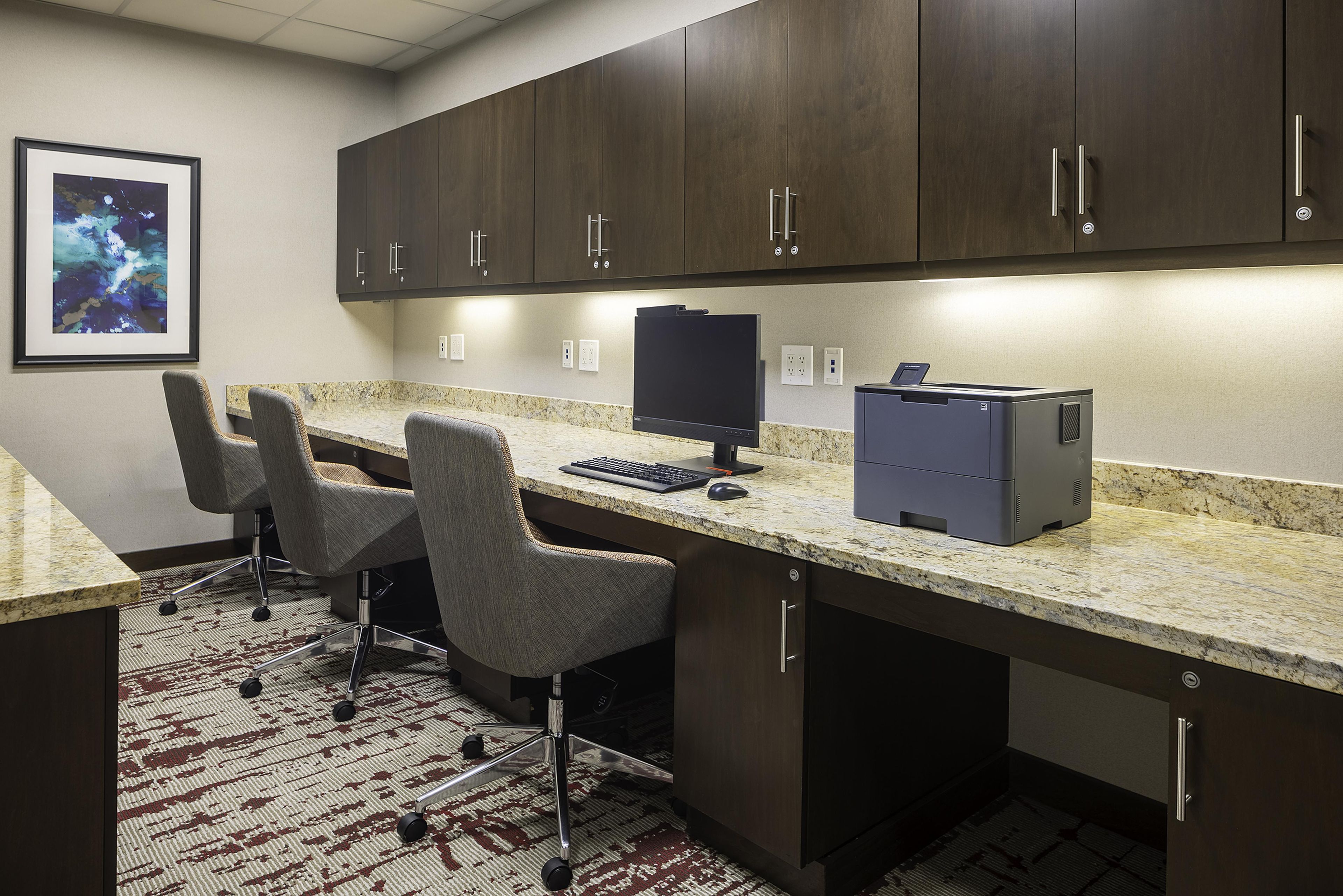 A modern office space with a desk, two chairs, a computer, and a printer.