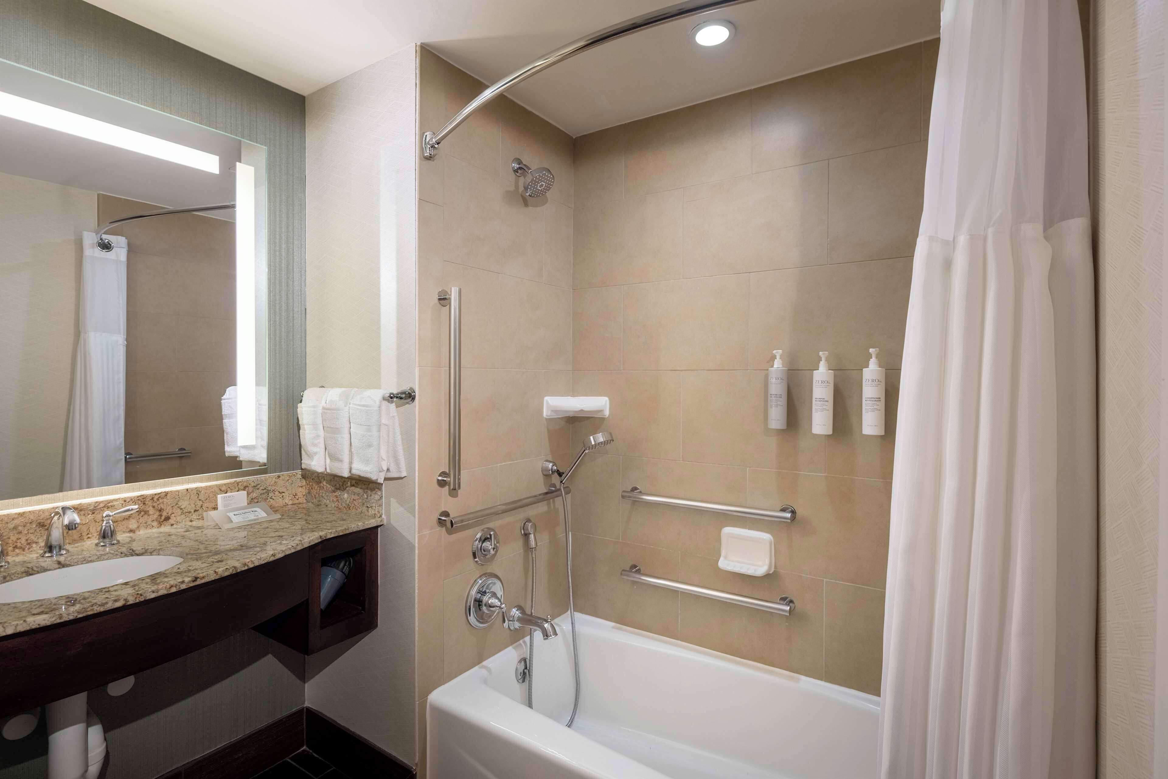 A modern bathroom with a bathtub, shower, and vanity.